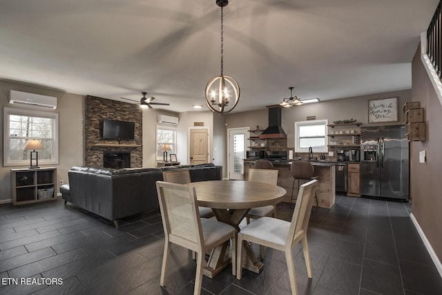 dining room featuring an AC wall unit, a stone fireplace, and plenty of natural light