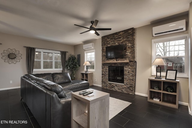 tiled living room featuring a wall unit AC, ceiling fan, and a stone fireplace