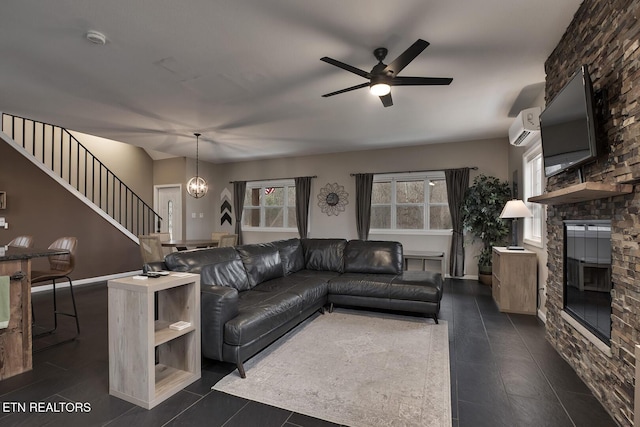 living room featuring an AC wall unit, a fireplace, and ceiling fan with notable chandelier