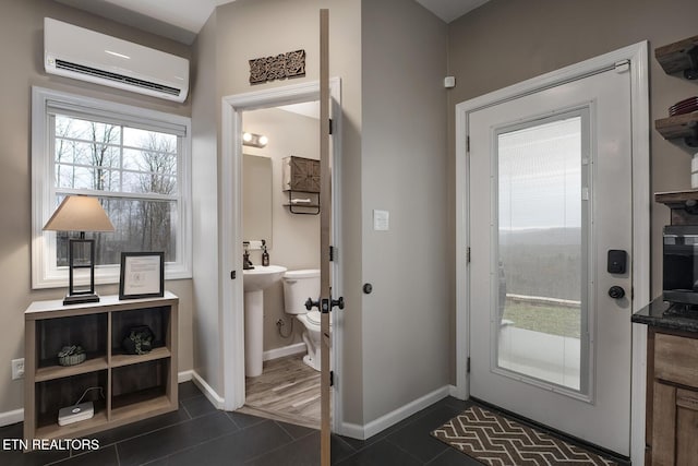 doorway to outside with dark tile patterned floors and a wall mounted AC