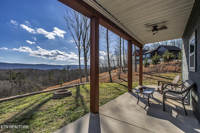 view of patio featuring a fire pit, ceiling fan, and a mountain view