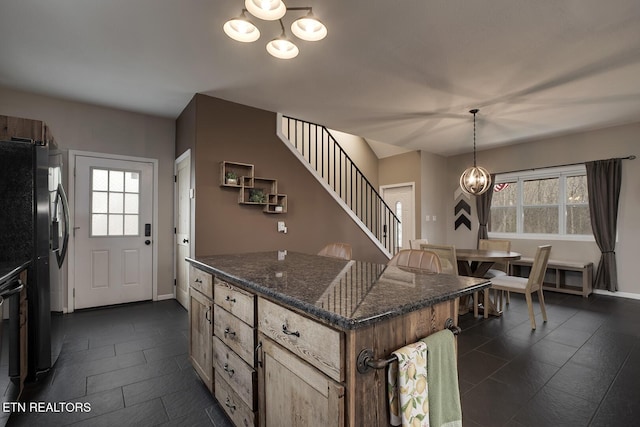 kitchen with decorative light fixtures, fridge with ice dispenser, a notable chandelier, dark stone countertops, and a center island