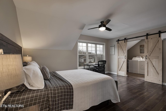 bedroom with lofted ceiling, ceiling fan, a barn door, washing machine and dryer, and dark hardwood / wood-style flooring