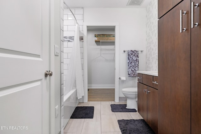 full bathroom featuring hardwood / wood-style flooring, vanity, shower / bath combination with curtain, and toilet