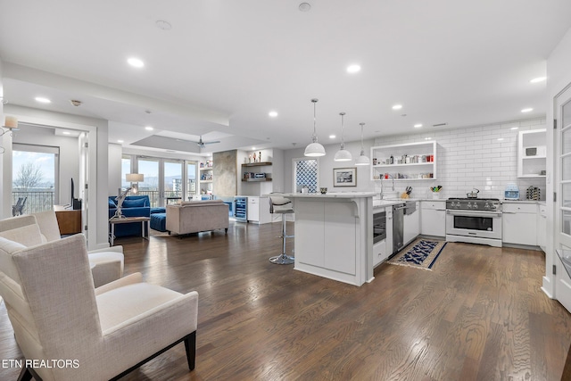 kitchen featuring white cabinets, hanging light fixtures, dark hardwood / wood-style flooring, a breakfast bar area, and stainless steel appliances