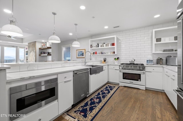 kitchen featuring sink, dark hardwood / wood-style floors, pendant lighting, white cabinets, and appliances with stainless steel finishes