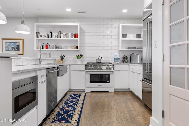 kitchen with hanging light fixtures, dark hardwood / wood-style flooring, decorative backsplash, white cabinets, and high end appliances