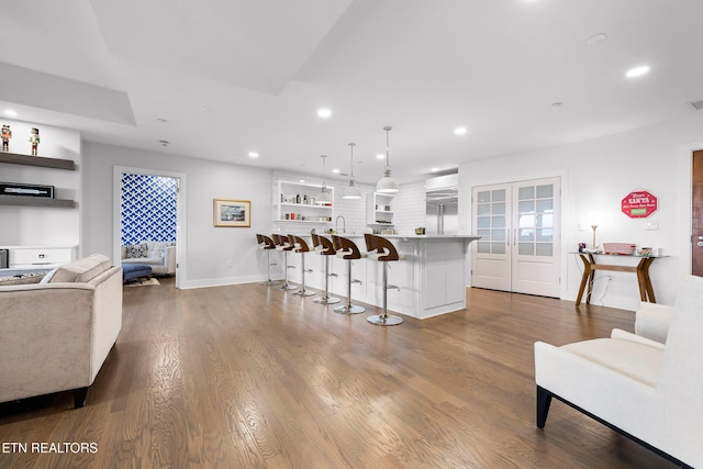 kitchen with pendant lighting, wood-type flooring, stainless steel built in fridge, a kitchen island, and a breakfast bar area