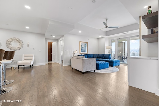 living room featuring ceiling fan and dark wood-type flooring