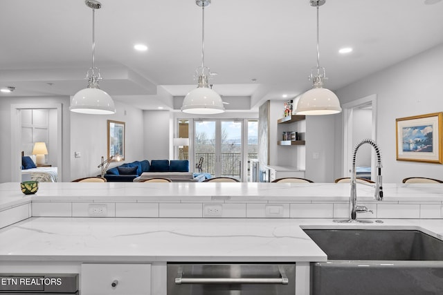 kitchen featuring light stone countertops, hanging light fixtures, and sink