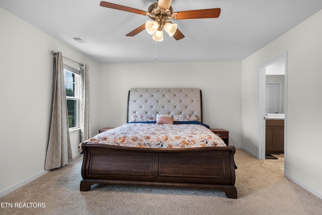 carpeted bedroom with ensuite bathroom and ceiling fan