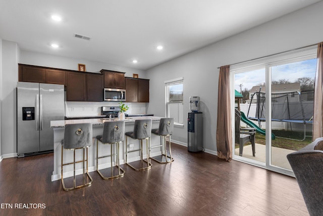 kitchen featuring dark brown cabinets, a center island, stainless steel appliances, and plenty of natural light