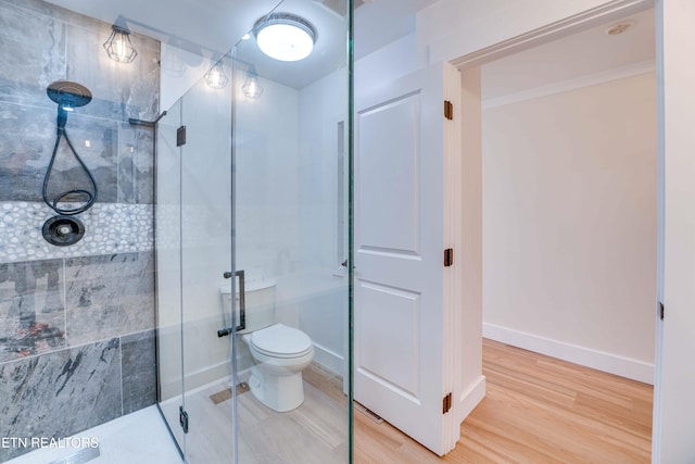 bathroom with wood-type flooring, a shower with shower door, and toilet