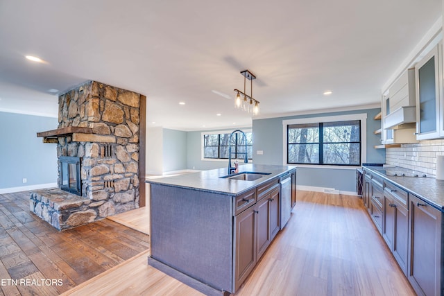 kitchen featuring tasteful backsplash, stainless steel dishwasher, sink, pendant lighting, and light hardwood / wood-style floors