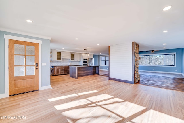 kitchen with decorative light fixtures, light hardwood / wood-style flooring, a breakfast bar, and tasteful backsplash