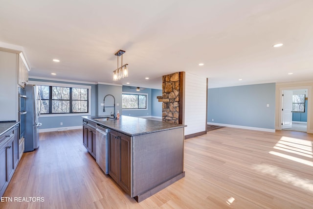 kitchen with sink, hanging light fixtures, an island with sink, light hardwood / wood-style floors, and stainless steel appliances