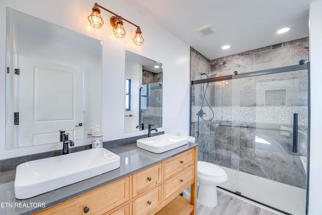 bathroom with hardwood / wood-style floors, vanity, toilet, and walk in shower