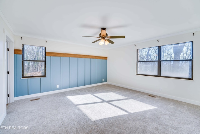 unfurnished room featuring ceiling fan, carpet floors, and crown molding