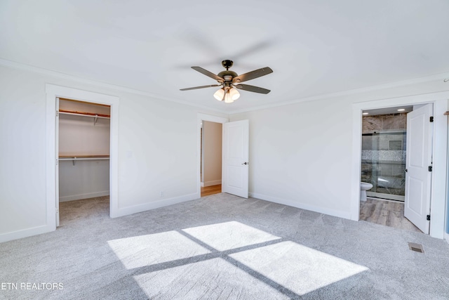 unfurnished bedroom with a closet, ensuite bath, a spacious closet, and ceiling fan