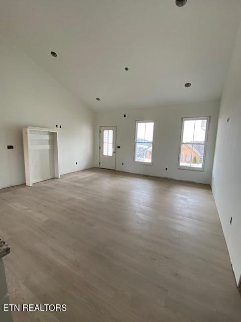 spare room with light hardwood / wood-style floors and high vaulted ceiling