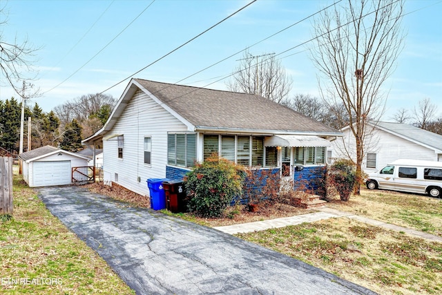 bungalow with an outbuilding, aphalt driveway, roof with shingles, and a garage