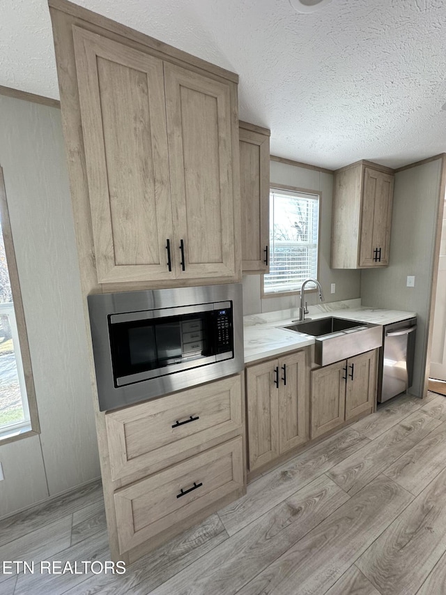 kitchen with a textured ceiling, appliances with stainless steel finishes, and light hardwood / wood-style flooring