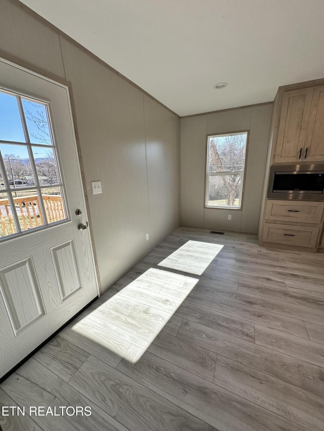 unfurnished dining area featuring light wood-type flooring and plenty of natural light