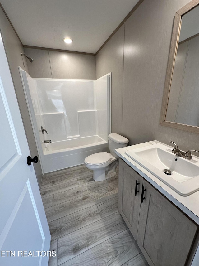 full bathroom featuring vanity, crown molding, hardwood / wood-style flooring, washtub / shower combination, and toilet