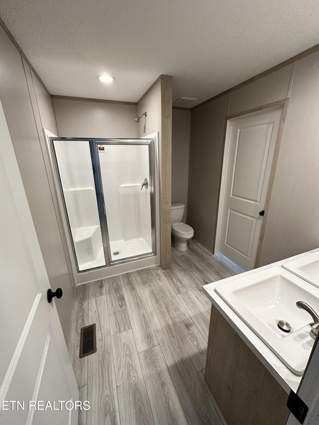 bathroom featuring hardwood / wood-style floors, a shower with door, and a textured ceiling