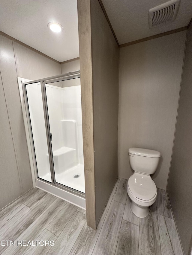 bathroom featuring walk in shower, toilet, and hardwood / wood-style flooring