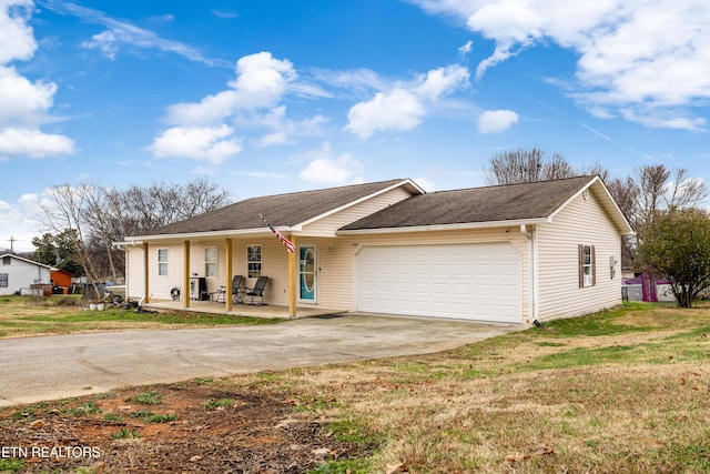 single story home with covered porch, a garage, and a front yard