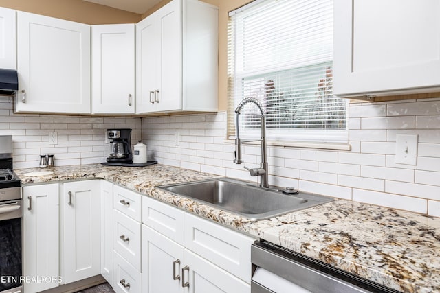 kitchen with appliances with stainless steel finishes, backsplash, white cabinetry, and sink