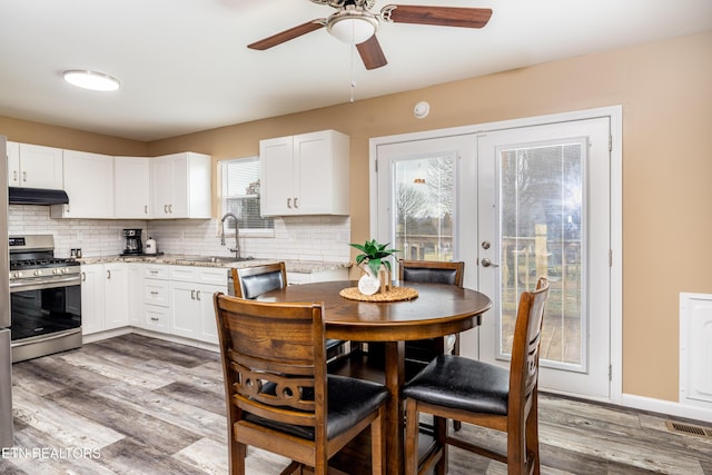 kitchen with hardwood / wood-style floors, french doors, white cabinets, sink, and stainless steel gas range