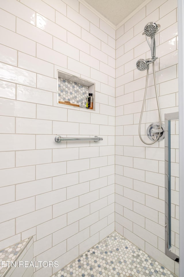 bathroom featuring a tile shower and ornamental molding