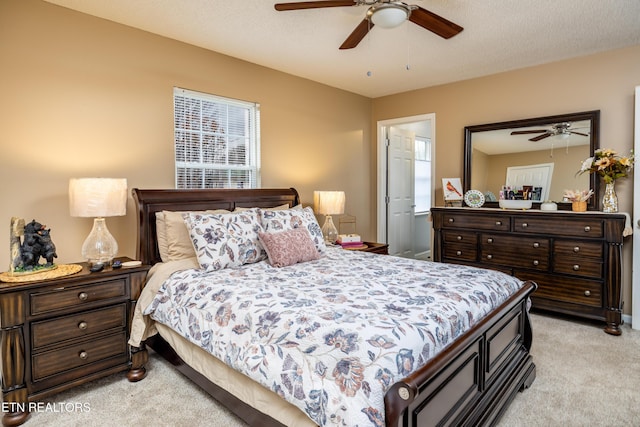 bedroom featuring ceiling fan, light colored carpet, and a textured ceiling