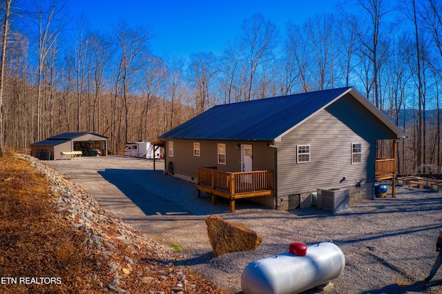 exterior space featuring central AC, an outbuilding, a deck, and a carport