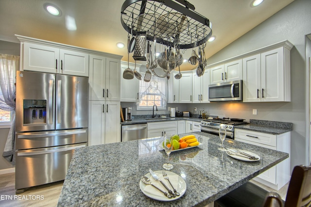 kitchen with white cabinets, sink, stainless steel appliances, and dark stone counters