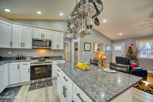 kitchen featuring white cabinets, light hardwood / wood-style floors, vaulted ceiling, and appliances with stainless steel finishes