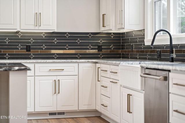 kitchen featuring dishwasher, white cabinets, and light stone countertops