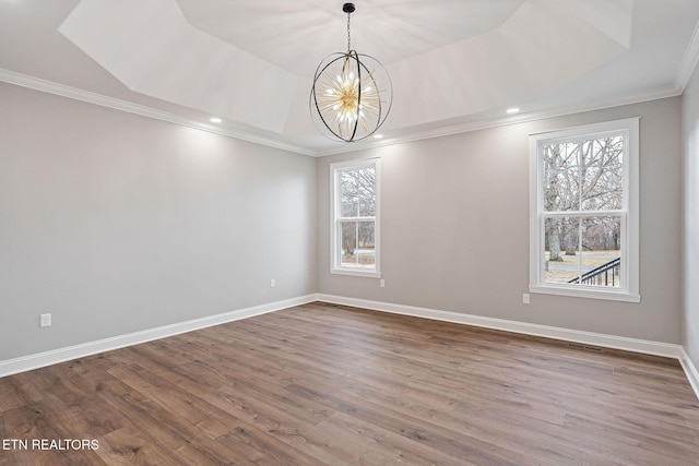 empty room with hardwood / wood-style flooring, crown molding, a tray ceiling, and a notable chandelier