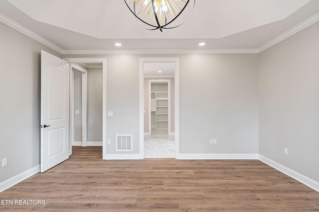 spare room featuring hardwood / wood-style floors, ornamental molding, and a notable chandelier