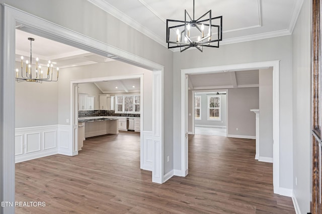 unfurnished dining area featuring crown molding, an inviting chandelier, and hardwood / wood-style flooring