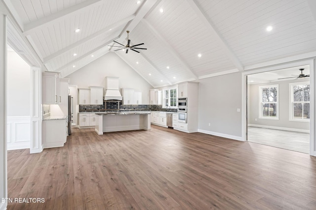 kitchen with white cabinets, light hardwood / wood-style floors, a kitchen island, and premium range hood