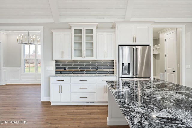 kitchen featuring tasteful backsplash, dark stone countertops, high end fridge, and white cabinets