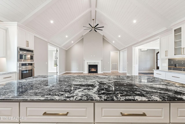 kitchen featuring white cabinets, ceiling fan, and dark stone counters