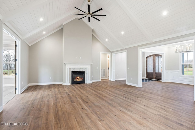 unfurnished living room with a premium fireplace, hardwood / wood-style floors, high vaulted ceiling, and french doors