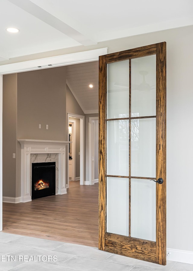 unfurnished living room with light wood-type flooring, a high end fireplace, and vaulted ceiling