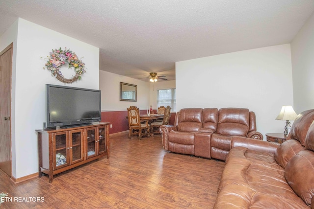 living room with hardwood / wood-style floors, ceiling fan, and a textured ceiling