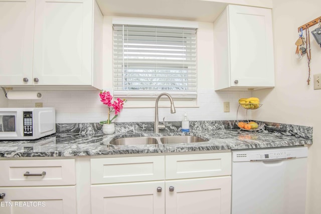 kitchen featuring white appliances, stone counters, white cabinets, sink, and tasteful backsplash