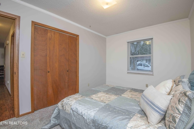 carpeted bedroom with a textured ceiling, a closet, and crown molding